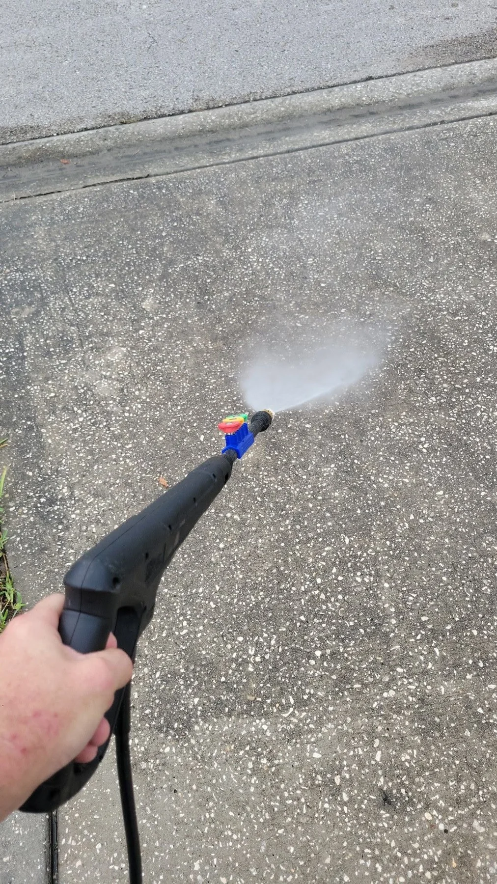 Ryan’s pressure washing equipment spraying a concrete surface